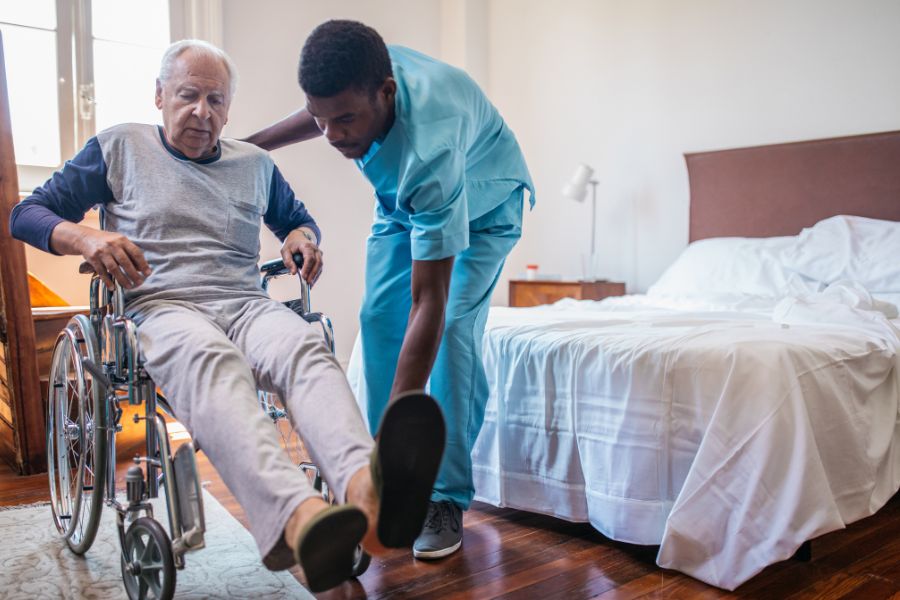 image presents black man assisting elder man in the wheelchair