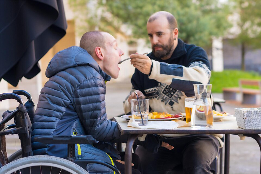 image presents feeding a disabled person in a wheelchair