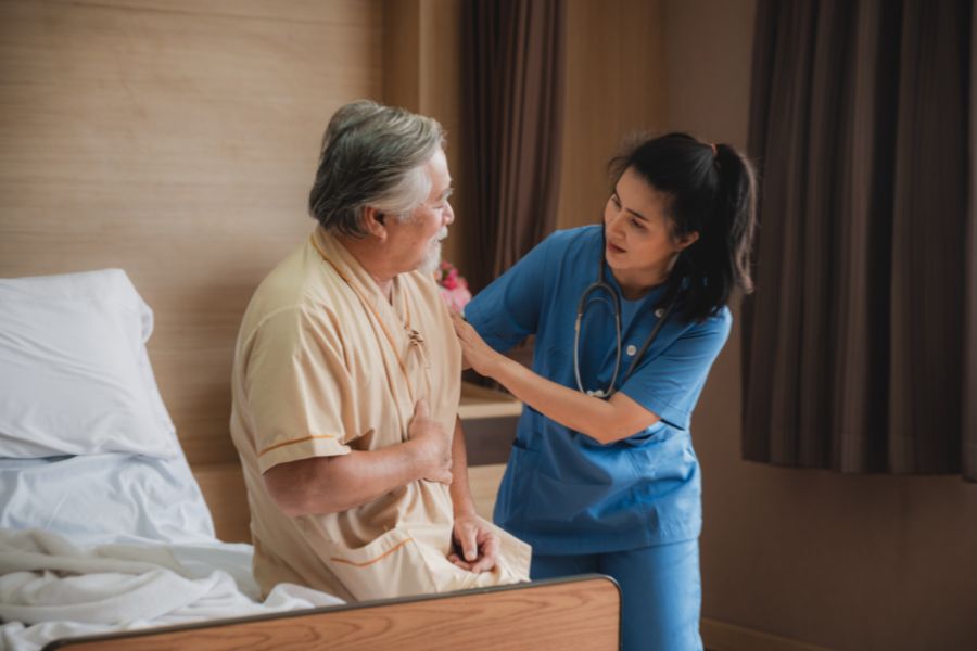 image presents nurse checking the chest of elder man