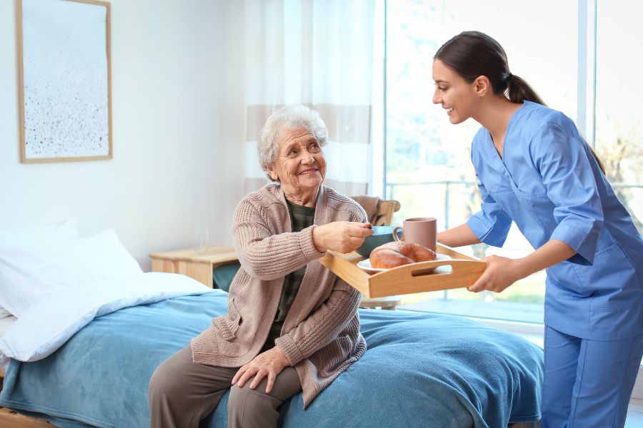 image presents nurse serving elder woman a food in a tray